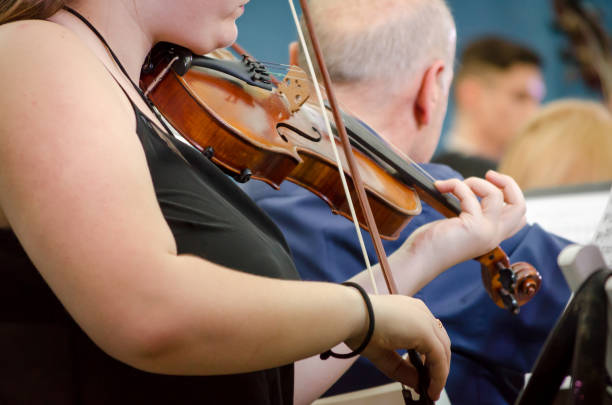 istock female musician playing a violin with a symphony orchestra 1156157896