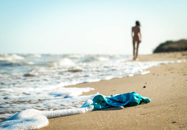 裸の女性の姿と青い空を背景に海のサーフの近くのビーチで砂の中の水着 - 裸 ストックフォトと画像