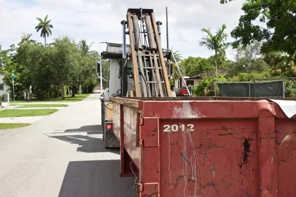 Empty roll-off construction dumpster being unloaded from truck at residential construction site