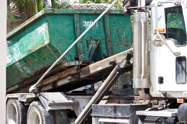 picking up full roll-off dumpster at residential site for efficient disposal