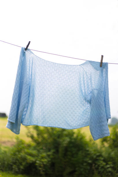 istock Rural Scene: Woman's Pale Blue Sweater on Laundry Line 1156164892