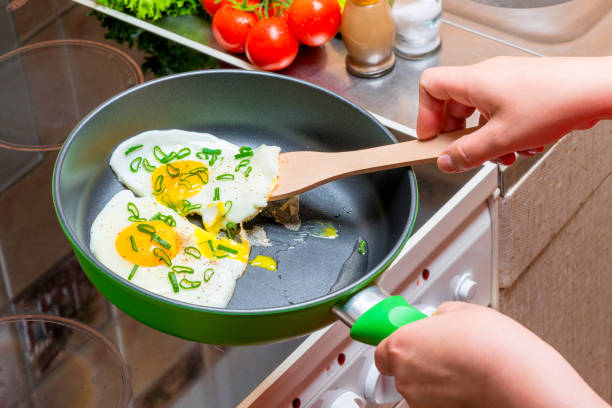 istock fried eggs on a griddle, hands with a wooden spatula close up 1156171361