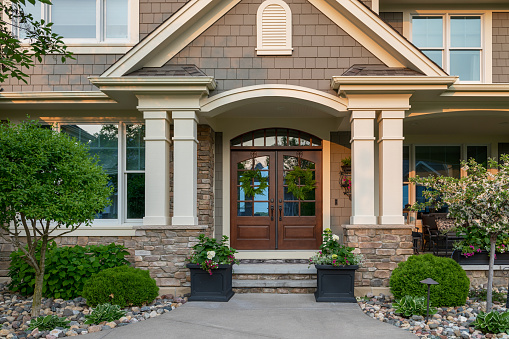 Oak Park, IL, USA - July 8, 2022: A new modern farmhouse with a white and brick siding, covered front porch, and beautiful landscaping.