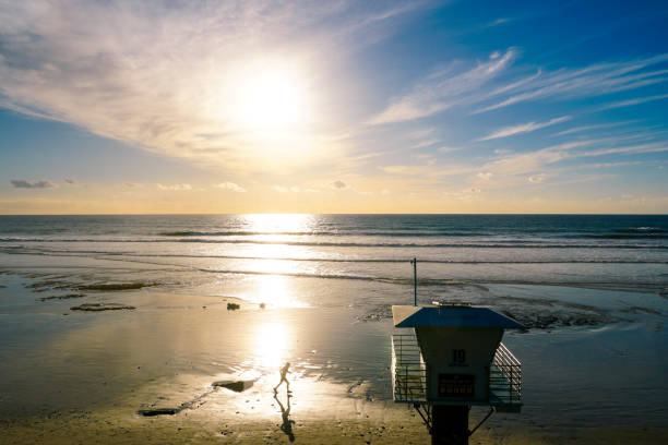 Blue lifeguard tower number 19 on a sandy beach with clouded blue sky sunny end of day, on Torrey Pines State Beach in California, located in San Diego County.