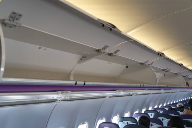 istock Carry-on luggage in overhead storage compartment on commercial airplane 1156197896