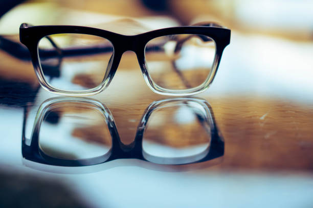 Eye glasses on wood table with  reflection
