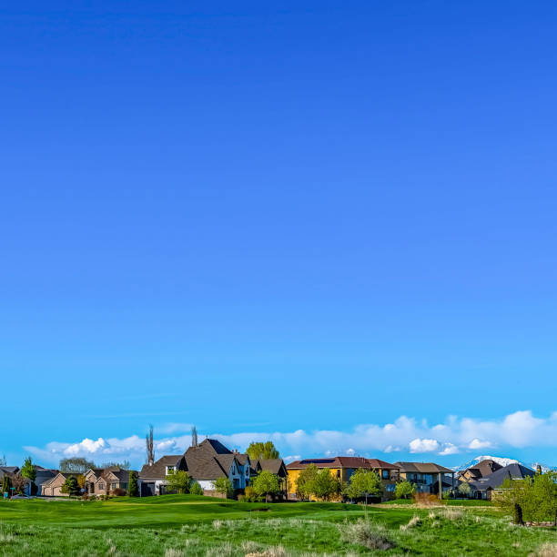 istock Square frame Vast grassy terrain with houses under blue sky and puffy clouds on a sunny day 1156207274