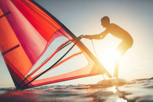 Windsurfer uplift sail for windsurf sailing Windsurfer uplift sail for windsurf sailing on sunset sea. windsurfing stock pictures, royalty-free photos & images