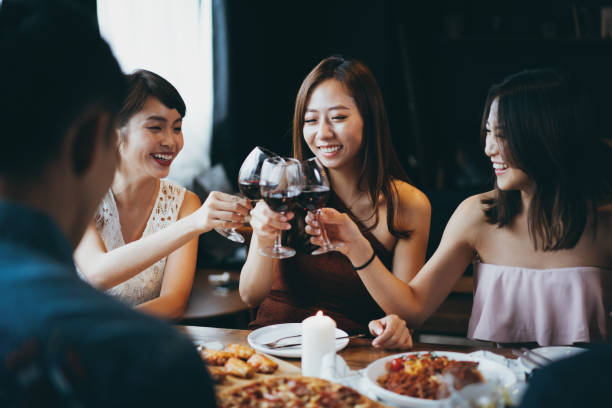 パーティー中に赤��ワインで楽しく乾杯する喜びに満ちたアジアの若い女性のグループ - women celebration wine party ストックフォトと画像