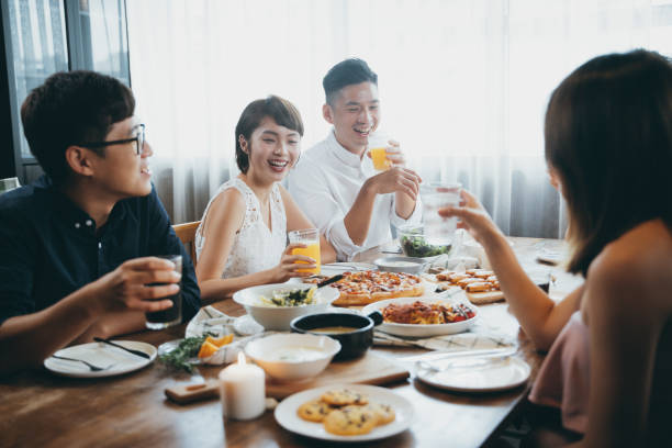 Group of joyful young Asian man and woman chatting, having fun and enjoying food and drinks during party Group of joyful young Asian man and woman chatting, having fun and enjoying food and drinks during party blind date stock pictures, royalty-free photos & images