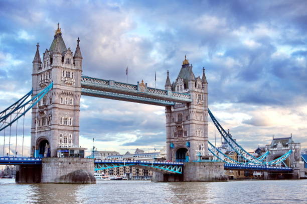 istock Tower Bridge at sunset over dramatic cloudy sky. Thames River water reflection present. 1156214692
