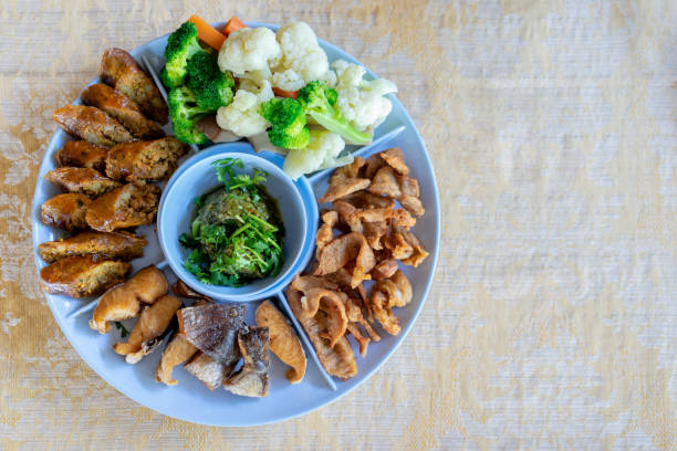 タイ北部のグリーンチリディップ(ナムプリクナム)は、サイアウ(タイ北部スパイシーソーセージ)、カリカリの割れ目、魚の揚げ物、ゆで野菜を添えたストリーキーポークとよく合いました。 - meat dusk cauliflower food ストックフォトと画像
