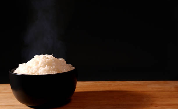 istock Rice in a black bowl and smoke on a black background. 1156223866