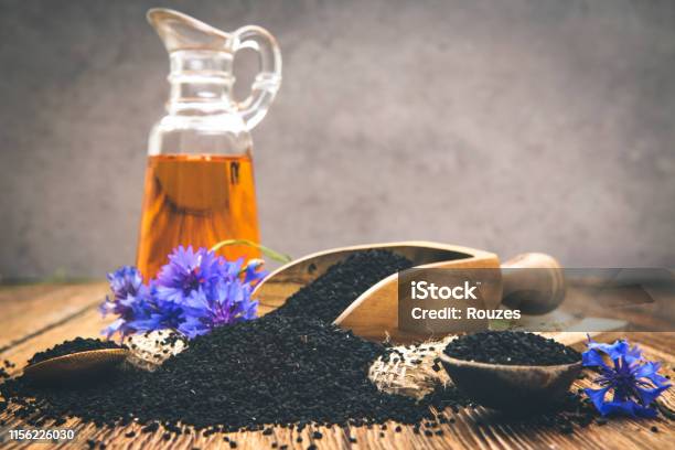 Black Cumin Seeds Essential Oil With Wooden Spoon And Shovel On Wooden Background Stock Photo - Download Image Now