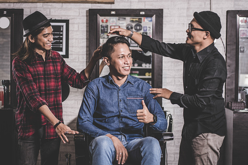 portrait of happy two barber with client standing and smiling at barberhop, hairstylisy and costumer interaction concept