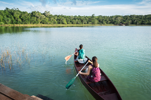 Multi-ethnic sisters canoeing.  Punta Laguna Nature Reserve, Tulum, Yucatan Peninsula, Quintana Roo, Mexico.
