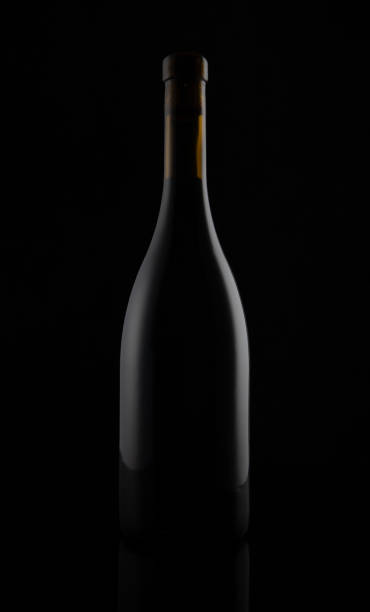 istock Isolated black matt wine bottle on dark background 1156228941