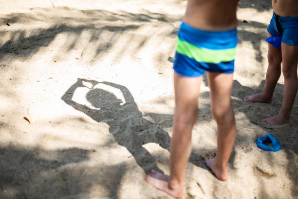 Happy boys playing in sand on the beach. They are from the back, making shadows and playing.