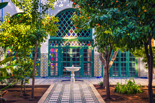 Marrakech, Morocco - January 10, 2019 : Small white fontaine among orange trees of Jardin Majorelle in Marrakech, Morocco