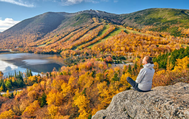 Woman hiking at Artist's Bluff in autumn Woman hiking at Artist's Bluff in autumn. View of Echo Lake. Fall colours in Franconia Notch State Park. White Mountain National Forest, New Hampshire, USA franconia new hampshire stock pictures, royalty-free photos & images