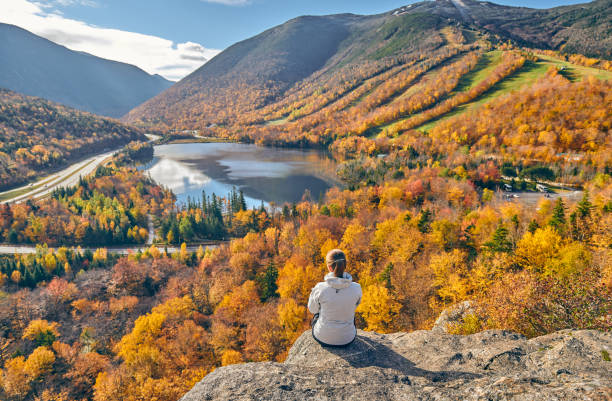 Woman hiking at Artist's Bluff in autumn Woman hiking at Artist's Bluff in autumn. View of Echo Lake. Fall colours in Franconia Notch State Park. White Mountain National Forest, New Hampshire, USA franconia new hampshire stock pictures, royalty-free photos & images