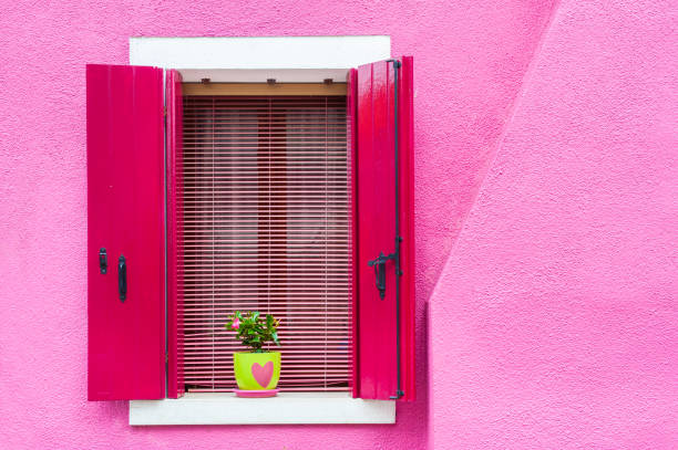 istock Window with pink shutters on the pink wall 1156239216