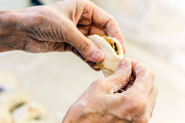 istock Dumplings. Dough with cabbage filling on the cook's hands 1156244077