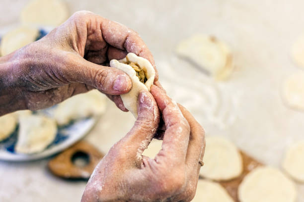 istock Dumplings. Dough with cabbage filling on the cook's hands 1156244084