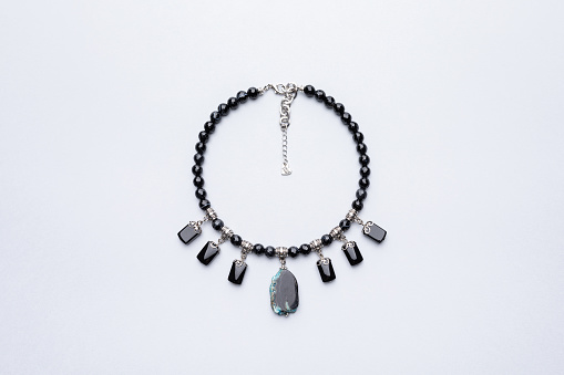 Flat lay handmade necklace with copy space. Top view agate stone and black onyx beads, studio photography concept. Beaded jewelry on gray background with negative space, product photography background.