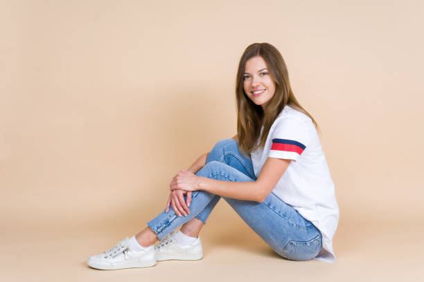 istock Young beautiful woman looking at camera, sitting on pastel beige background with copy space 1156245031