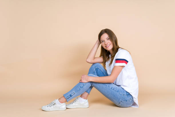 istock Young beautiful woman looking at camera, sitting on pastel beige background with copy space 1156245166