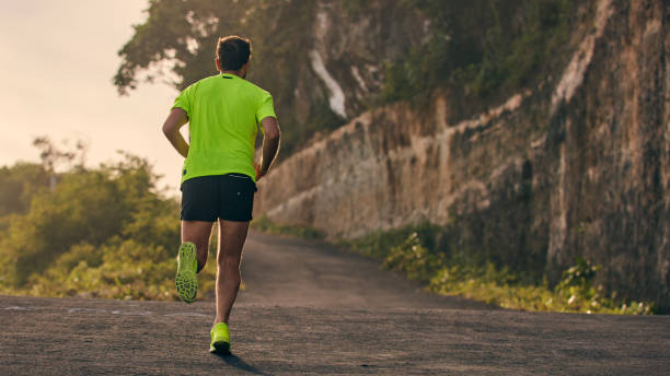 istock Man jogging on a downhill / uphill in suburb mountain road. 1156246251