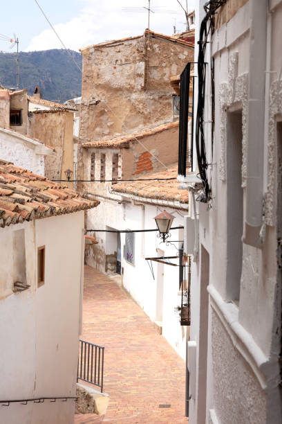 narrow street in Chelva, Spain, with the facades painted in white, water route