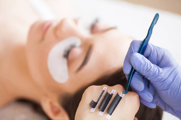 istock Eyelashes extensions. Fake Eyelashes. Eyelash Extension Procedure. Professional stylist lengthening female lashes. Master and a client in a beauty salon 1156247130