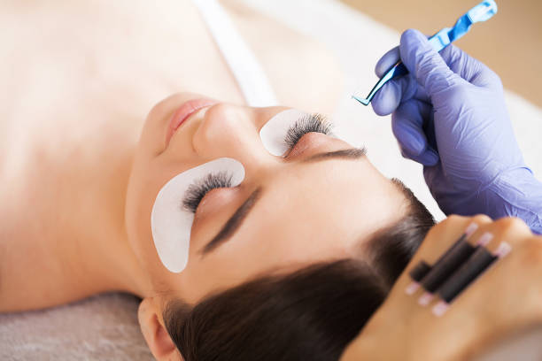 istock Eyelashes extensions. Fake Eyelashes. Eyelash Extension Procedure. Professional stylist lengthening female lashes. Master and a client in a beauty salon 1156247513