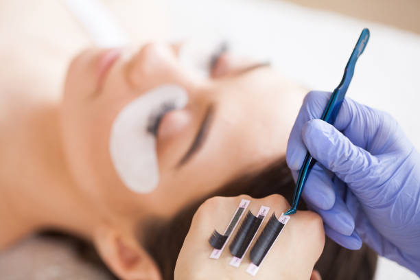 istock Eyelashes extensions. Fake Eyelashes. Eyelash Extension Procedure. Professional stylist lengthening female lashes. Master and a client in a beauty salon 1156247599