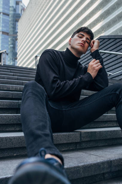 istock Handsome man in black clothing sitting on stairs 1156248654