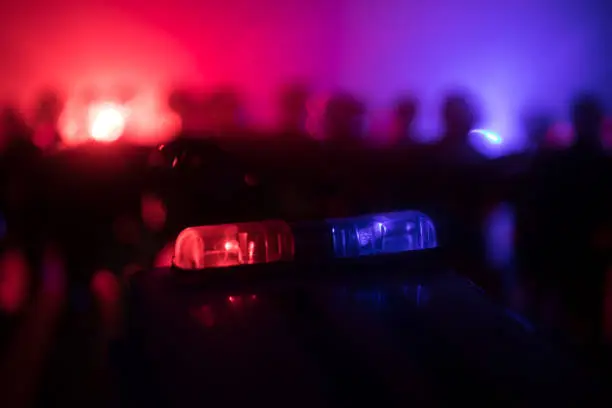 Photo of Anti-riot police give signal to be ready. Government power concept. Police in action. Smoke on a dark background with lights. Blue red flashing sirens.