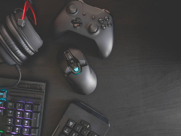istock gamer workspace concept, top view a gaming gear, mouse, keyboard, joystick, headset, mobile joystick and mouse pad on black table background with RGB color. 1156258348