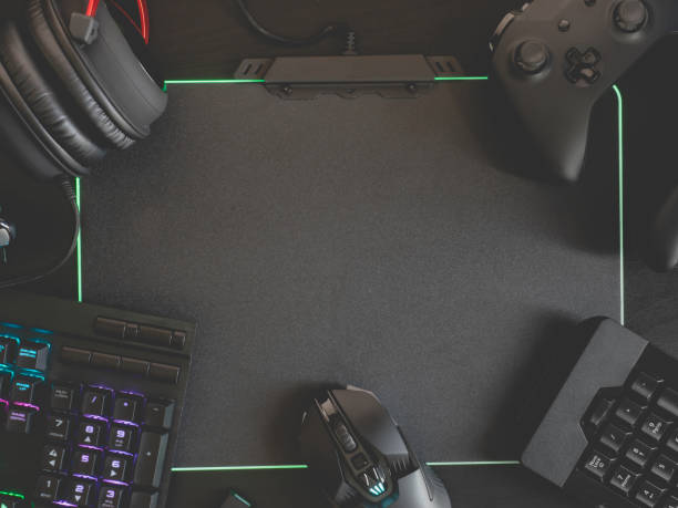 istock gamer workspace concept, top view a gaming gear, mouse, keyboard, joystick, headset, mobile joystick and mouse pad on black table background with RGB color. 1156258365