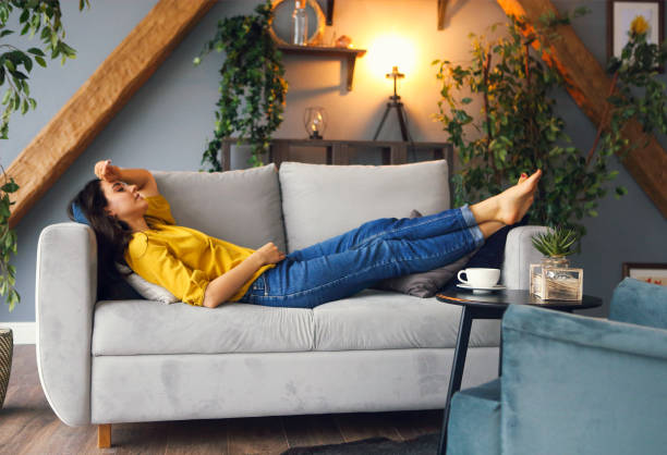 Young brunette woman relaxing on the couch after a long day Young brunette woman relaxing on the couch after a long day. Cozy home concept lying down stock pictures, royalty-free photos & images
