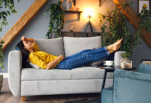 Photo of Young brunette woman relaxing on the couch after a long day