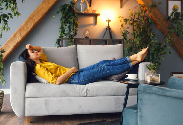 young brunette woman relaxing on the couch after a long day - lying down imagens e fotografias de stock