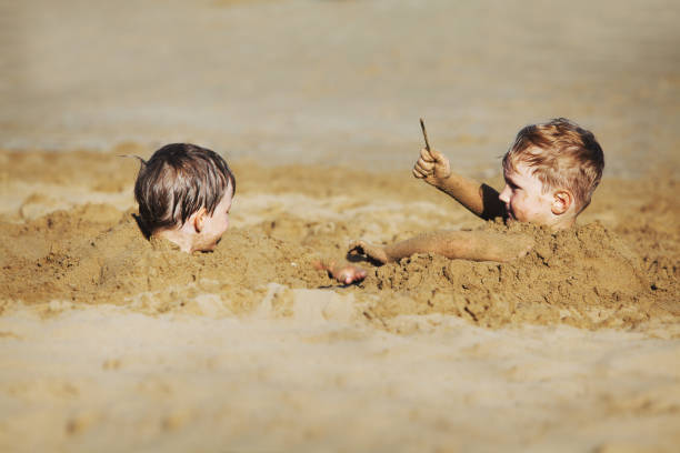 Little boys at the beach playing with sand