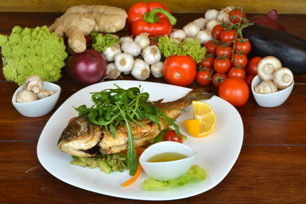 istock Bream fish served with dipping sauce and rocket salad on top 1156269247