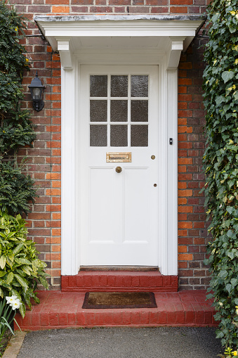 Front door of a period English house with white wooden half glazed door