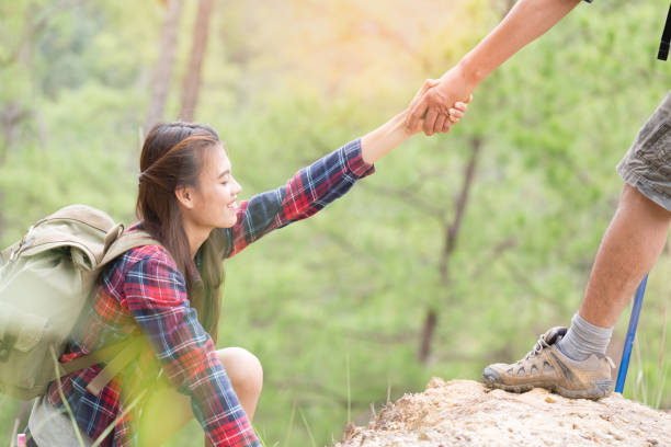istock Man help pull a woman's hand in hiking activities on the mountain, teamwork and hiking concept. 1156275493