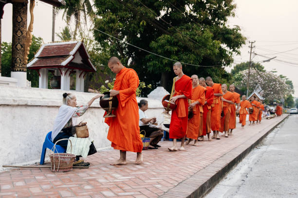 Luang Prabang Traditional Alms giving ceremony, Laos APR 4, 2019 Luang Prabang, Laos - Traditional Alms giving ceremony of distributing food to buddhist monks on the streets alms stock pictures, royalty-free photos & images