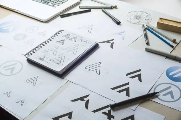 Photo of Graphic designer development process drawing sketch design creative Ideas draft Logo product trademark label brand artwork. Graphic designer studio Concept.