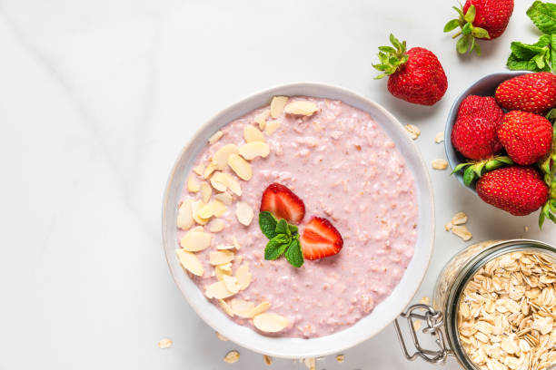 istock overnight oats with fresh strawberries, almonds and mint in a bowl on white marble table. healthy breakfast 1156278236